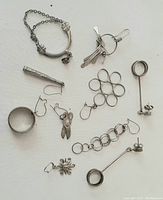 Lot of assorted small sterling silver jewelry pieces including bracelet, pendants, earrings, and rings arranged on white background