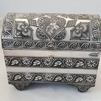 Front view of the silver chest jewelry box showing the lock, ornate engraving, and feet.
