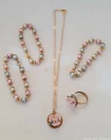 Full set showing two beaded bracelets, ring, and necklace with pink flower pendant