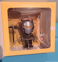 Front view of the Fortnite Omega figure in packaging showing the figure and accessories inside a yellow box.