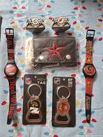 Front view of all items including 2 sports watches, 1 wallet, 2 key chain bottle openers in packages, and 2 card holders.
