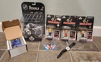 Lot overview showing Tampa Bay Buccaneers watch, four Headliners hockey figures, Vesa Toskala action figure, and box of hockey cards.