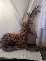 Photo showing the full wooden decorative reindeer made of intertwined twigs, positioned laying down.