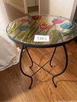 Side view of the round table with metal legs and colorful floral glass top