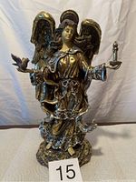 Front view of gold coloured angel figurine holding bird and candle