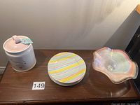 Photo showing the cookie jar, stacked dessert plates with pastel stripes, and pastel ruffled bowl on a wooden surface.