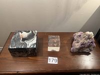 The entire lot on a wooden surface showing the wooden box, lucite cube with quartz inclusion, and a large quartz chunk