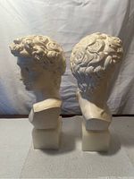 Front and back view of the two bust bookends showing detailed curls and facial features on cream-colored Stonelite figurines on square bases.
