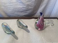 Photo showing two polar bear glass paperweights and one decorative bird glass paperweight on a white textured surface with a neutral background.