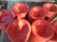 Multiple stacks of orange ceramic bowls, total quantity 48, showing smooth curved interiors and consistent orange color.