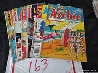 Seven Archie comic books arranged on a dark surface showing colorful covers, including Archie #498, Life With Archie edition, and others.