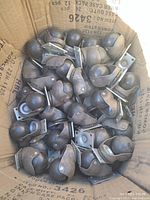 Box filled with approximately 30 metal and rubber ball caster wheels with mounting brackets.