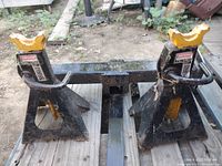 Pair of used Craftsman jack stands with black bodies and yellow top supports positioned on wooden surface outdoors.