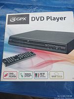 Box of GPX DVD player showing product image and features like remote control and A/V cables included.