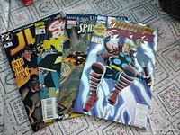 Four comic books displayed together showing front covers: JLA Classified #3, Ghost Rider #57, Sensational Spider-Man #29, Thunderstrike #1