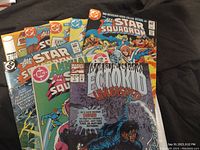 Photo showing multiple comic books including All Star Squadron issues, Annual #1, Ecto Kid #1, and Cyberforce #2 with visible cover artwork.