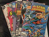 View of multiple comic books including All Star Squadron, Starfire, The Outsiders, and Captain America showing front covers.