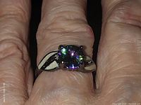 Close-up image of ring on finger showing square-cut purple stone and silver-tone band