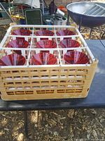 Nine red margarita/martini/dessert glasses arranged inside a beige plastic dishwasher rack.