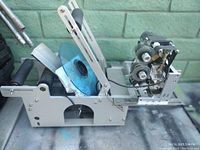 Side view showing the mechanical frame with label roll holder, adjustment arm, and internal rollers.