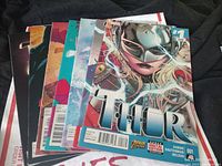 Seven female Thor comic issues spread out showing covers including issue #1 with female Thor on front.