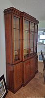 Full view of the wooden vintage hutch showing the upper glass cabinet with two doors and lower solid wood cabinet.