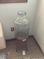 Clear glass jug on metal stool showing overall size and placement in a corner