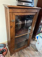 Front view showing single glass-paneled door and three interior shelves