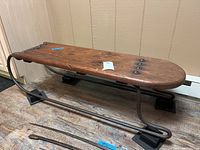 Overview of antique sled from front angle showing wood seat and metal runners
