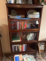 Full view of assembled four-section barrister bookcase with topper and base, items inside placeholder