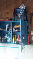 Blue metal storage cabinet containing various automotive fluids and products with JNC 660 Jump Starter on top