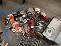 Wide assortment of Chrysler keychains, uncut keys, ashtray, metal case, cologne bottle arranged on floor