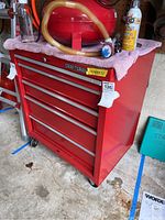 Red Craftsman five drawer toolbox on wheels with pink cloth and some items on top, viewed from front and side angles.
