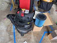 Top view of the Craftsman vacuum with hose attached and three new filters in a box beside it.