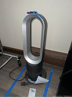 Full frontal view of the Dyson Hot+Cool tower with remote placed on top and power cord visible