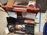 Top view of open orange and black FEIN carrying case containing the orange and black FEIN MultiMaster FMM250Q tool, various accessories, and manuals.