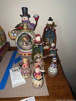 Full collection of Jim Shore snowmen figurines, music box, and hanging ornaments arranged on table.