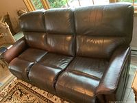 Full view of dark brown leather reclining sofa showing three seats, armrests, and padded backrests.