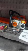 Stihl MS 180C chainsaw with bar cover and accessories on tray