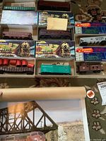 Multiple HO scale Lehigh Valley model train cars in original boxes, some loose, and a rolled railroad poster tube on a patterned carpet.