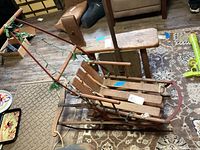 Angle view of the vintage wooden sled showing metal frame and wooden slats with a push handle at the rear.