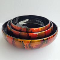 View of three nesting lacquerware bowls with abstract cactus print showing black interior and burnt orange/red/green metallic exterior.