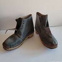 Side angle of antique leather boots with copper toe caps and wooden soles