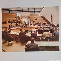 Cardboard print showing Toronto City Council meeting room with councilors seated at desks in semicircle.