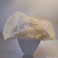 Front view of vintage white lace bridal wedding wire hat with wide brim, showing the lace detail and shape.