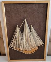 Full front view showing the sailboat nail string art piece fully framed with burlap background.