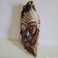 Full view of the Native American chief wall sculpture showing detailed feather headdress and natural wood base.