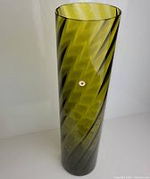 Full view of a tall cylindrical vase in emerald green with spiral swirl pattern.