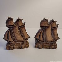 Front view of both tall ship schooner boat bookends showing detailed resin sailboats in brown.
