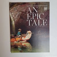 Front cover of 'An Epic Tale' book showing a man paddling a historic canoe inside a cave, reflective water below, and the title in white text.